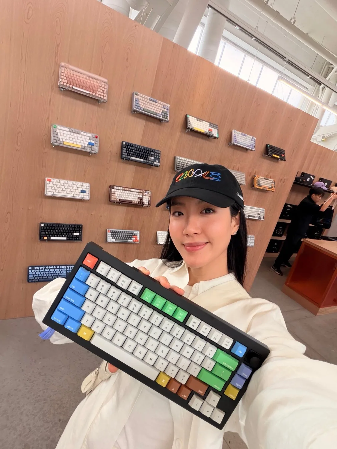 An attendee holding a custom Keychron keyboard in front of the keyboard wall